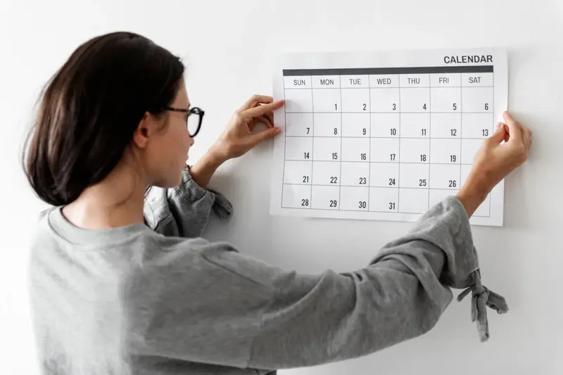 Femme consultant un calendrier mural pour vérifier une date