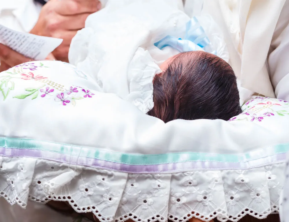 Nouveau-né emmailloté sur un coussin brodé et bordé de dentelle, lors d’une cérémonie juive