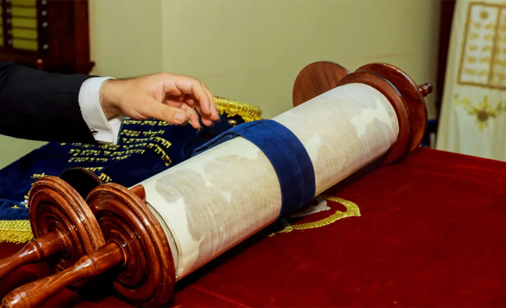 Rouleau de la Torah ouvert sur la table de lecture d’une synagogue, sur un tissu de velours rouge